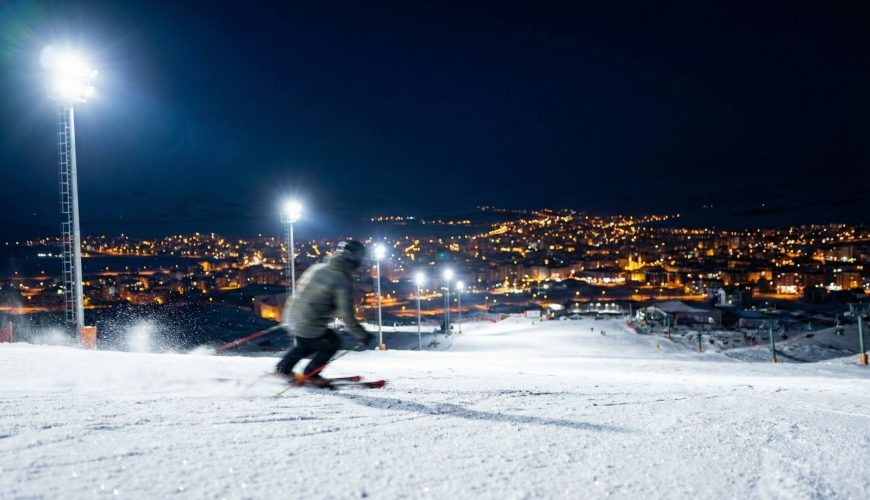 Palandöken’de gece kayağı yapan bir sporcu ve ışıklandırılmış kayak pistleri