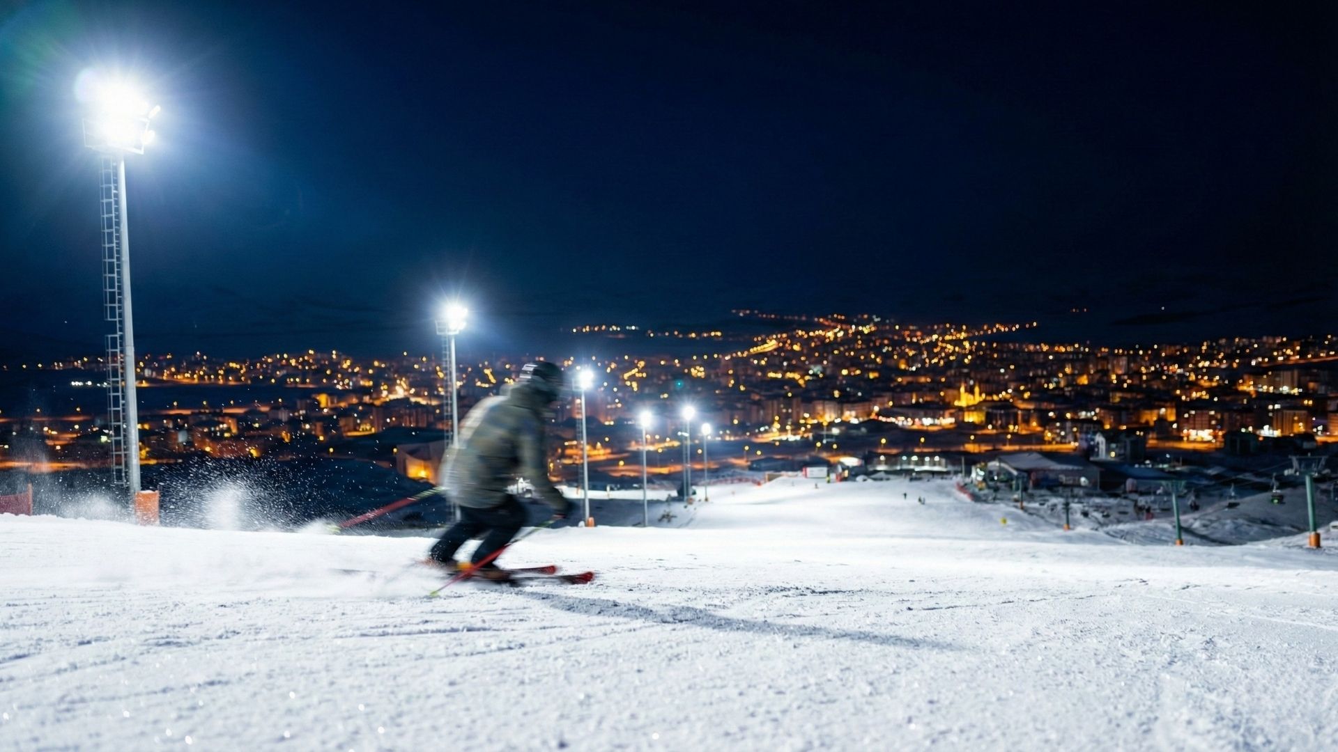 Palandöken’de gece kayağı yapan bir sporcu ve ışıklandırılmış kayak pistleri